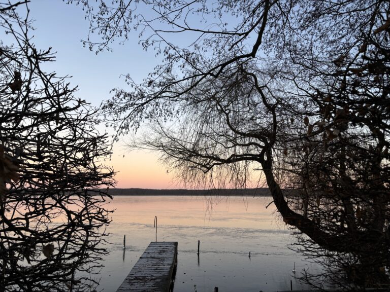 Blick auf den Mellensee bei Sonnenuntergang mit Steg und Bäumen