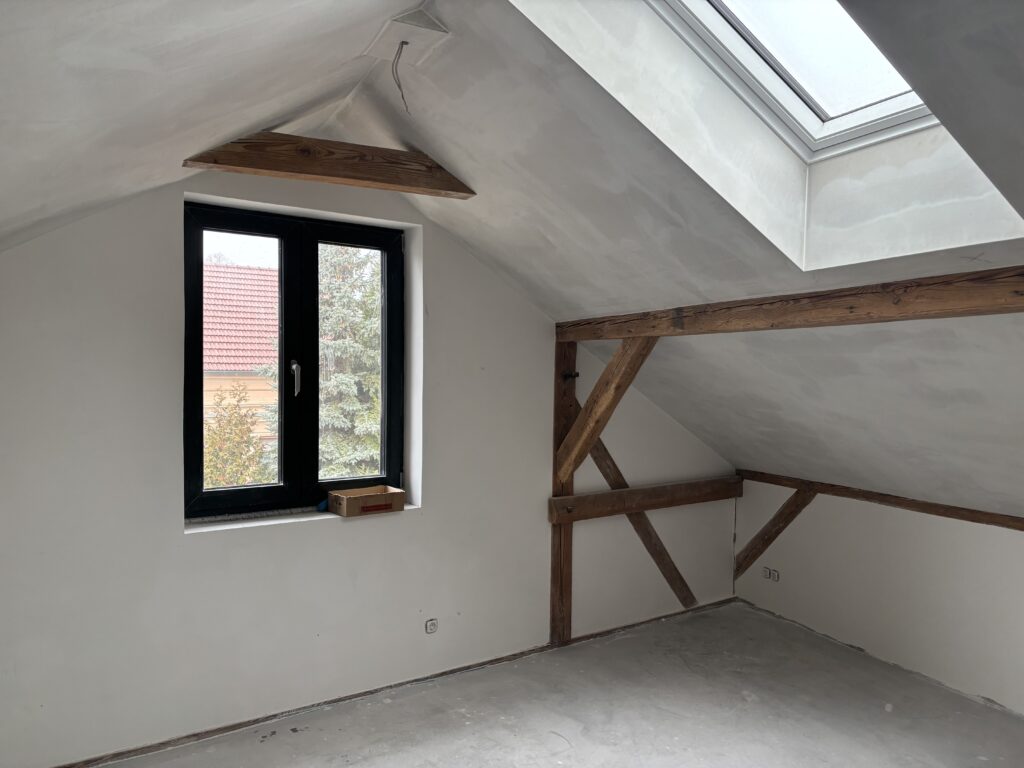 Schlafzimmer mit Dachschrägen, Holzbalken, Doppelbett und Fenster