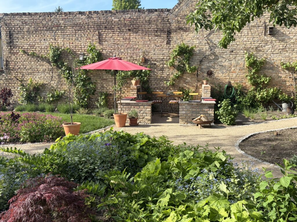 Gemauerte Terrasse im Garten mit Sonnenschirm und Liegewiese